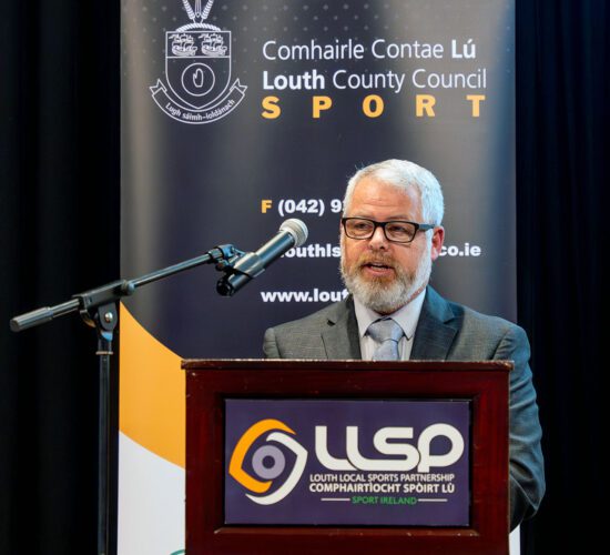 Mr. Graham Russell speaking into microphone on a podium.