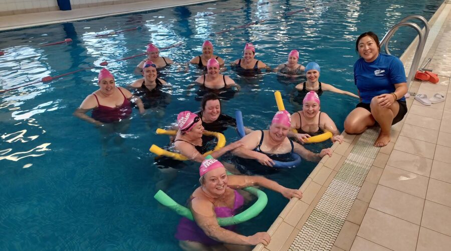 Group of women swim in pool.