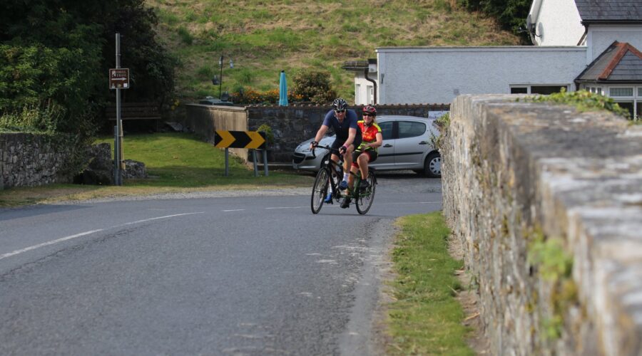 Man and woman cycling around a bend in road.