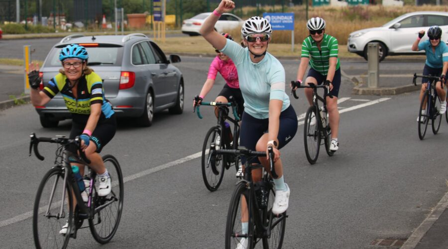 Women cycle on their bikes on road.