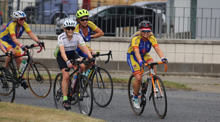Women cycle their bikes around a bend.