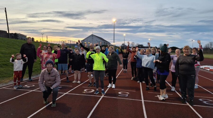 Moneymore Hub - Group of people on running track with hands in air.