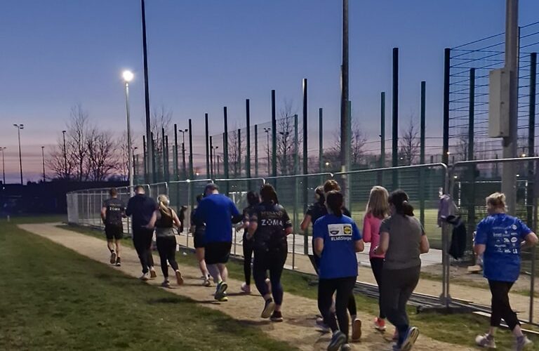 Moneymore Hub - Group of people running along dirt path at night.
