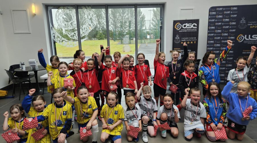 Young children post in sports tops with medals around necks.