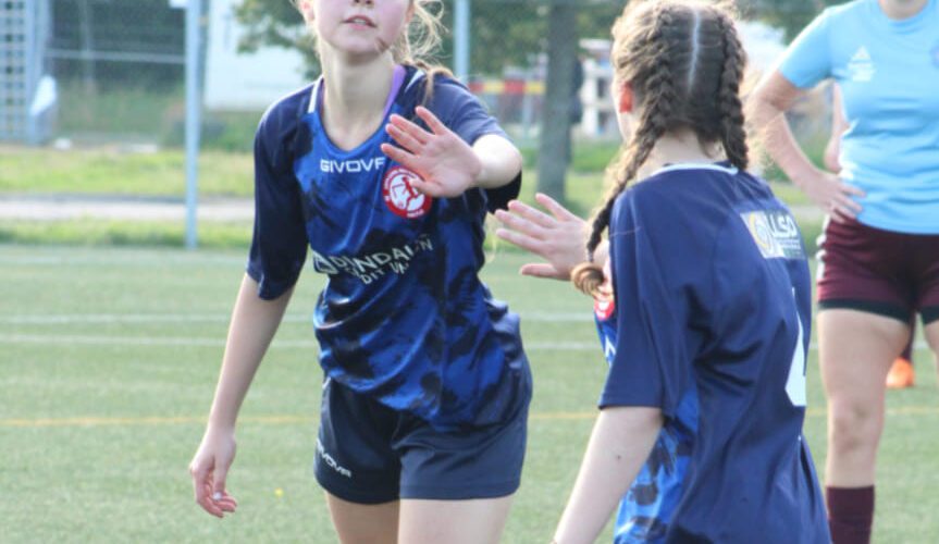 Two young soccer players high five.
