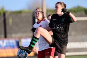 Two girls play soccer.
