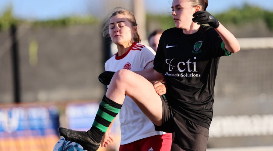 Two girls play soccer.