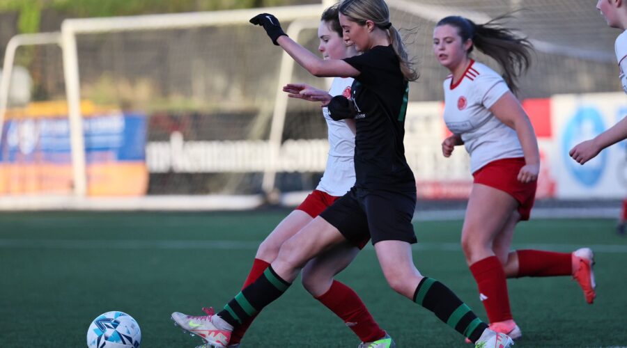 Young girls tackle for soccer ball.