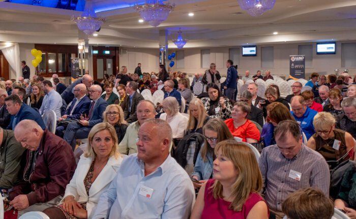 A group of people sit in chairs at an award ceremony facing the stage.