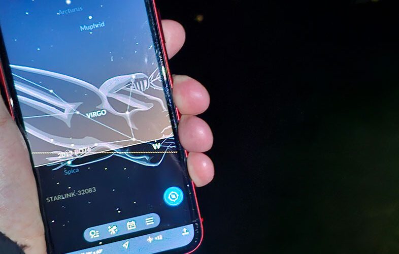 A person holds a phone up to show star alignments.