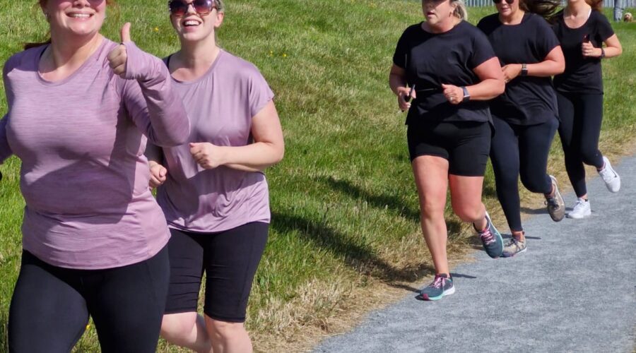 Muirhevnamor Hub - Group of five women run along path on a sunny day.