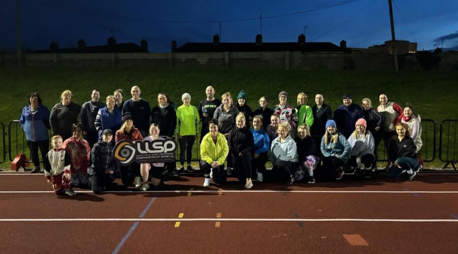 Moneymore Hub - Couch to 5k Connect Group stand on running track at night.