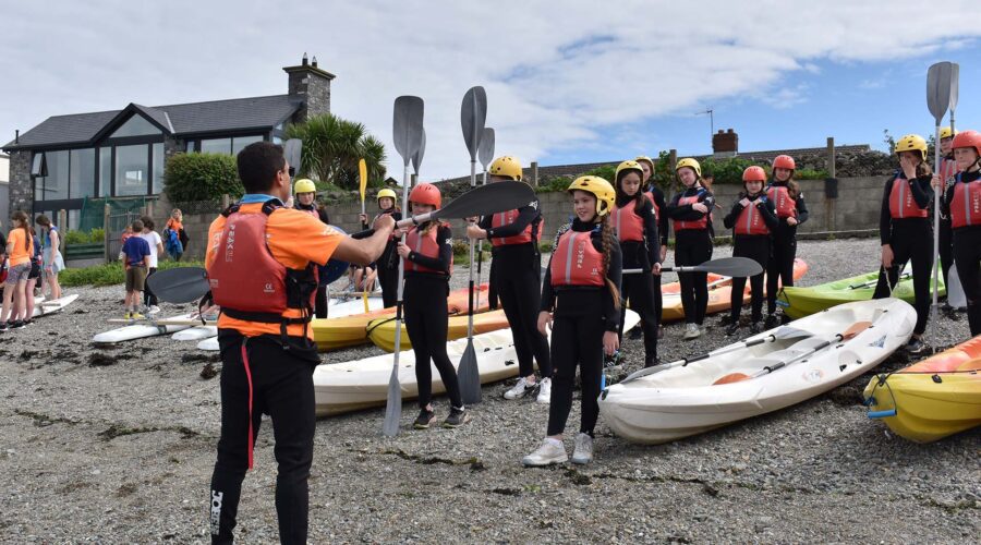 Young girls in wetsuits learm how to hold oars.