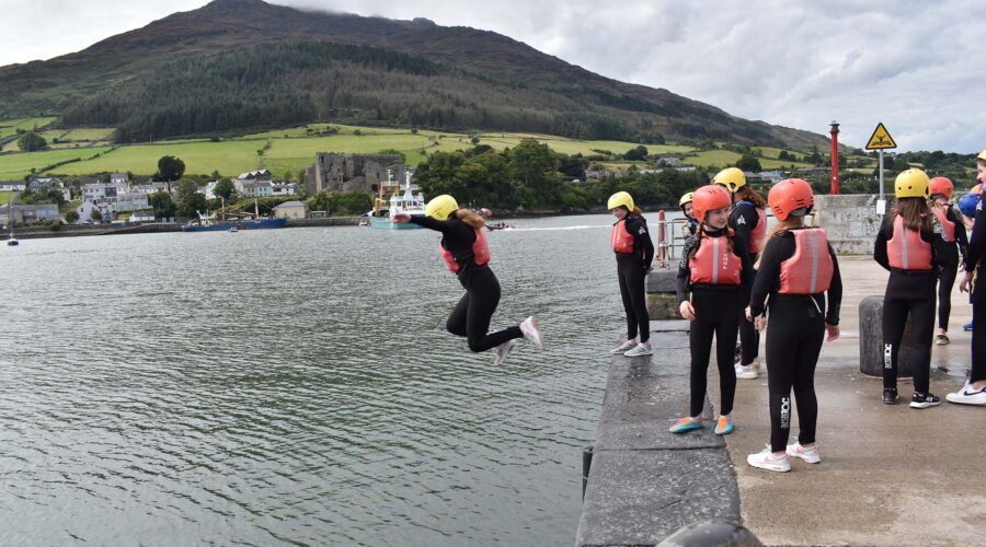 Young girl jumps off of pier into water.