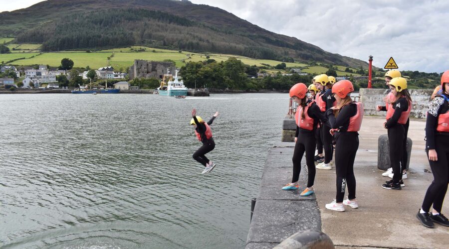 Young girl jumps off of pier into water.