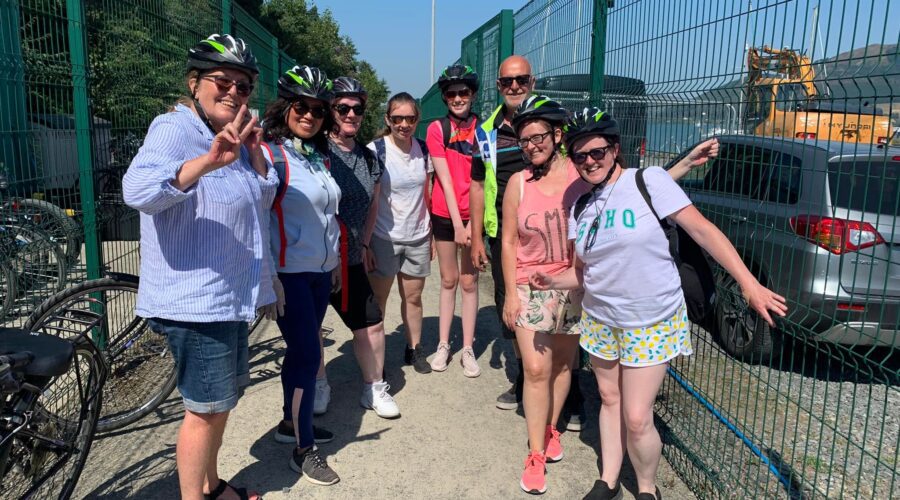 Group of people with cycling helmets on smile at camera.