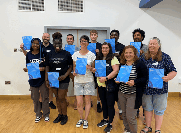Group of people proudly holding their blue Safeguarding diplomas.