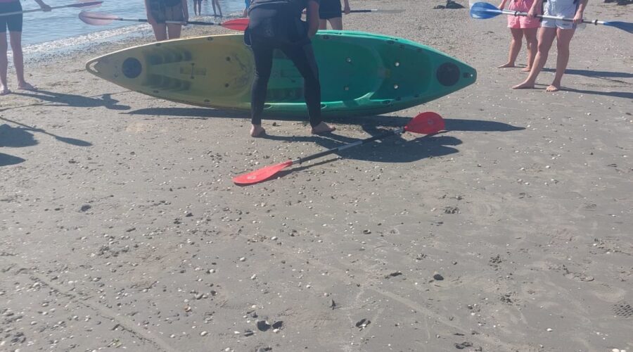 Women setting up kayak on a beach.