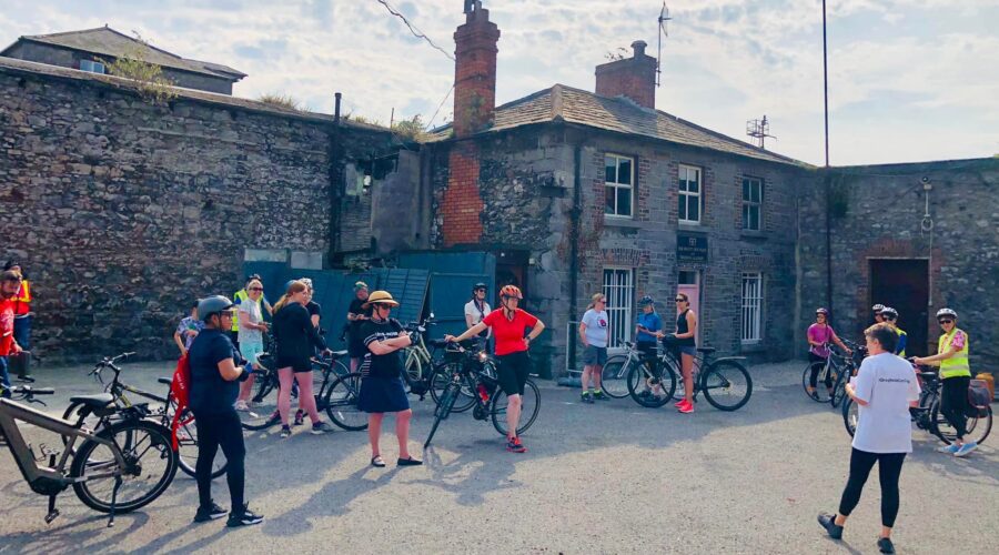 Group of women stand by bikes in a courtayard.