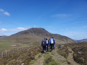 Group of girls walk towards mountain summit.