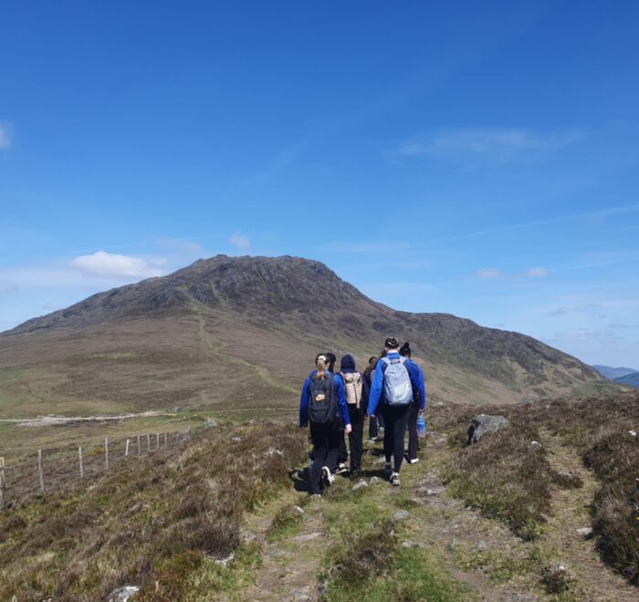 Group of girls walk towards mountain summit.