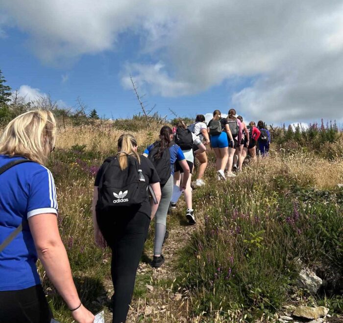 Group of girls climb trail.