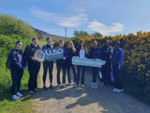 Group of girls hold signage on walking trail for LLSP.
