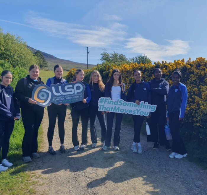 Group of girls hold signage on walking trail for LLSP.