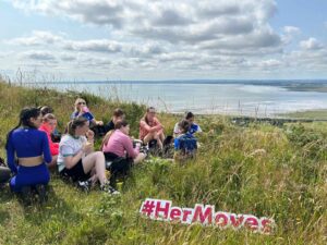 Group of girls take rest off beaten track with scenic views of water.