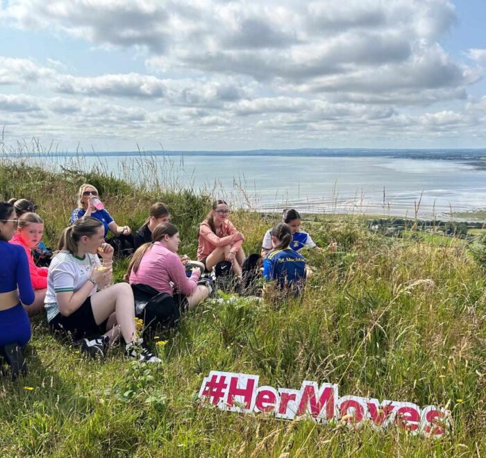 Group of girls take rest off beaten track with scenic views of water.