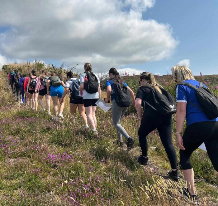 Group of girls continue uphill on trail.