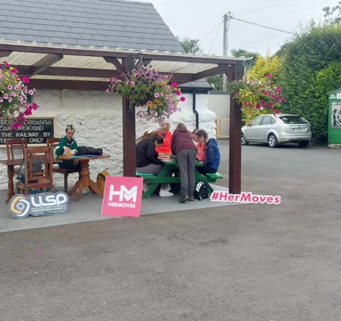 Group of girls site at green picnic bench.