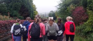 Group of girls walk along road with backs turned to camera.