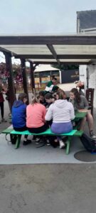 Group of girls site at green picnic bench.