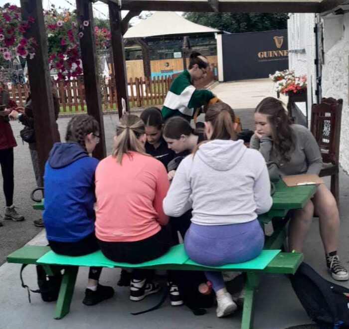 Group of girls site at green picnic bench.