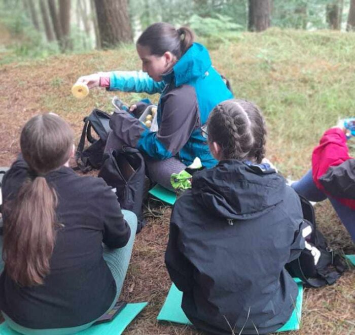 Group of girls share food while on nature trail.