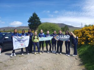 Group of girls hold sign for Summit Sisters and LLSP.