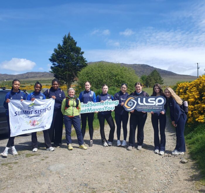Group of girls hold sign for Summit Sisters and LLSP.