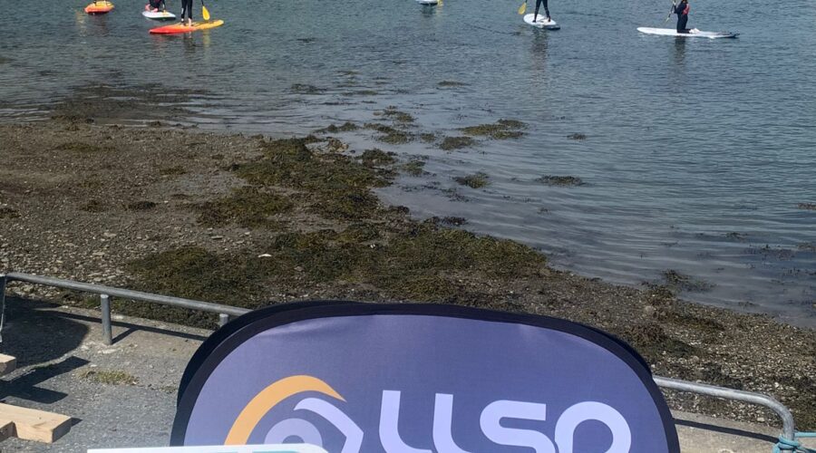 Signage of LLSP with group of people paddle boarding in the distance.
