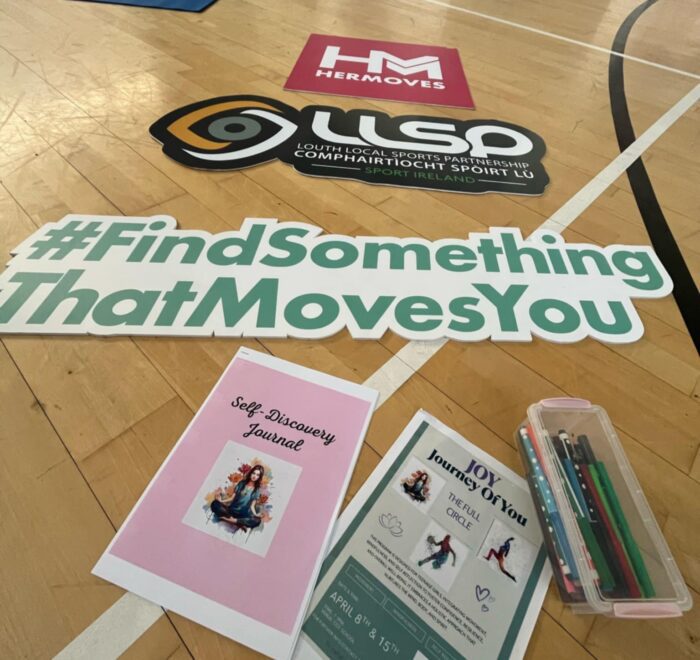 Signage for Her Moves is laid out on floor of gym.