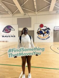 Girl holds sign that says #FindSomethingThatMovesYou while in gym.
