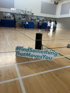 #FindSomethingThatMovesYou sign stands next to yoga mat in gym.