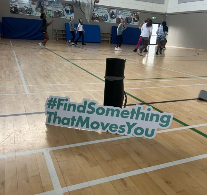 #FindSomethingThatMovesYou sign stands next to yoga mat in gym.