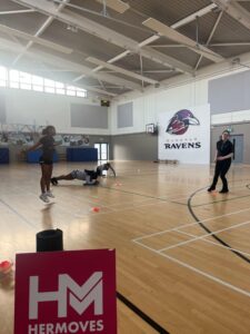 Girls work out in gym near sign for Her Moves.