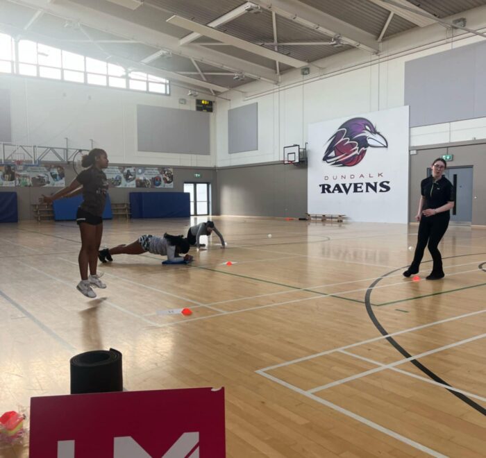 Girls work out in gym near sign for Her Moves.