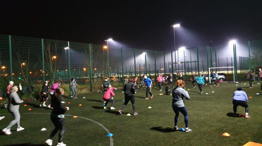 Moneymore Hub - Bootcamp of people squatting on astroturf pitch.