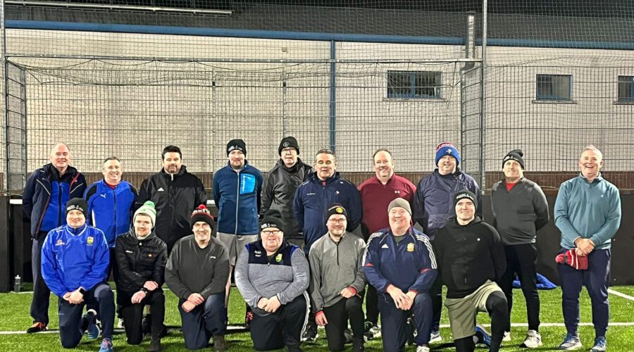 Men on the Move - Group of men pose for picture on an astroturf pitch.