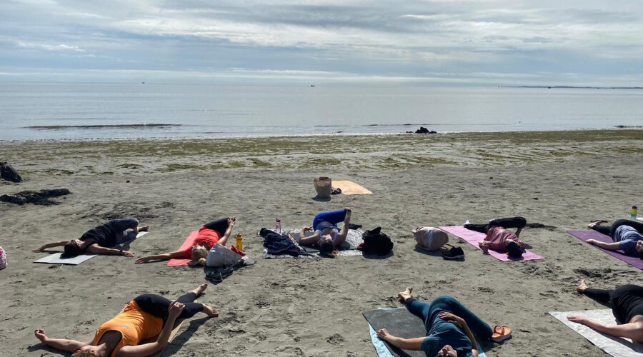 Women do pilates on the beach.