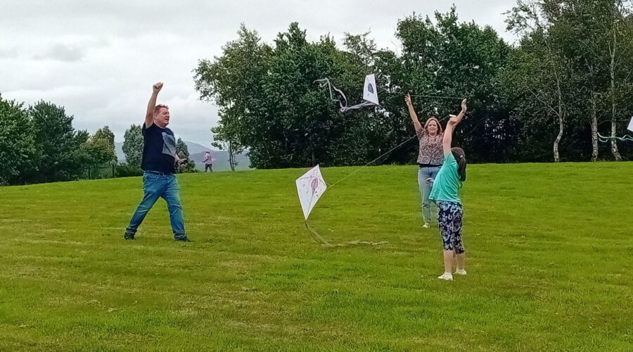 Family of three play with kites in a park.