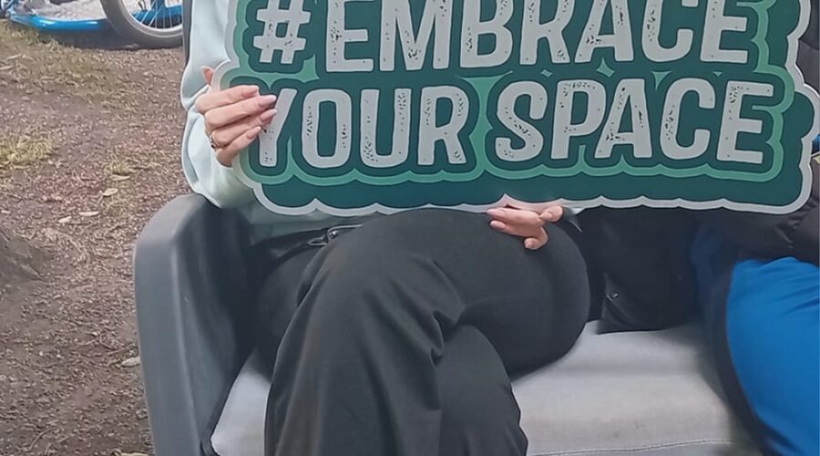 Woman site and hold sign for #EmbraceYourSpace